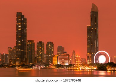 Blurred abstract background of high-rise buildings built by the river, lit at night, the distribution of residences of today's capital society. - Shutterstock ID 1873795948