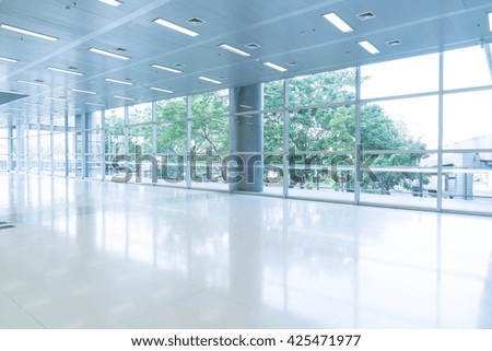 Blurred abstract background interior view looking out toward to empty office lobby and entrance doors and glass curtain wall with frame - blue white balance processing style