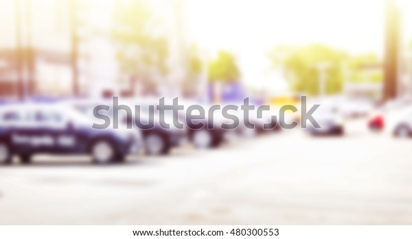 Blurred abstract background of new undefined\
cars in a row in front of dealership\
