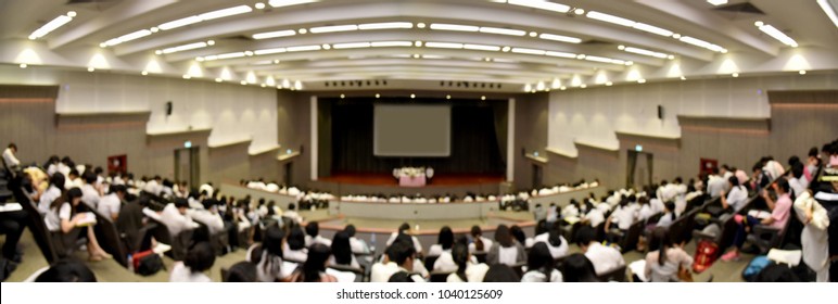 Blurred Abstract Background Panorama Of New Students, Audience And Keynote Speaker For Freshman Orientation Day In International Conference Hall During Graduation Ceremony. Event University Or Campus.