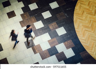 Blurred Abstract Background. Silhouettes Of Two People Walking In A Public Building Hall Top View. Motion Blur Technique Of Low Speed Shot. Blur Silhouettes Of People's. Low Speed Shutter Shot.