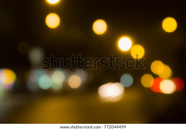 Blurred abstract\
background. The street lights in a blur. Evening or night city.\
Light of shop Windows and\
cars.