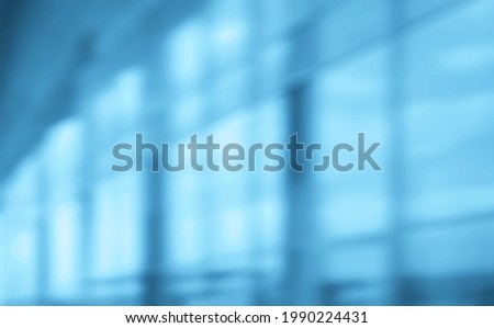 Blurred abstract blue glass wall from building background. Business building blur background office lobby hall interior empty indoor room with blurry light from glass wall window