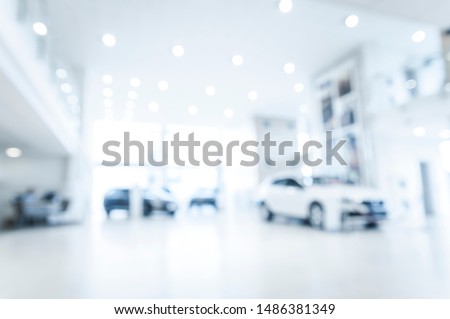 Blurred abstract dealership store, with defocused cars, clients and staff with  soft lightning
