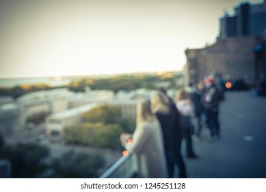 Blurred Abstract Diverse Group Of People In Formal Dress Hanging Out At Rooftop Bar In Downtown Chicago, USA. Business Happy Hour Concept, Autumn Season