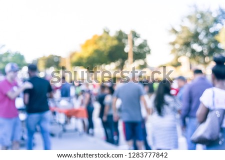 Blurred abstract diverse group of people queuing for free meals at local Church festival near Dallas, Texas, USA. Defocused line of multicultural family members at outdoor food serving line
