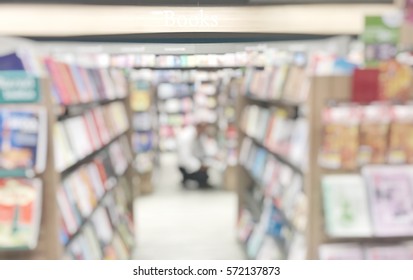 Blurred abstract image man squat down for choosing a book on shelves in book shop. Blurry view person sitting to looking for select books on shelf in book store. Blur lifestyle for background usage. 