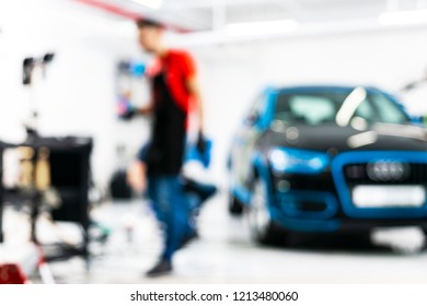 Blurred Abstract Image Of Man Worker With Car In Body Shop. Blur Car Auto Service. Car Bokeh. Blurred Background With Car In Garage. Vehicle Maintenance In Auto Repair Service. Blurry Service Station