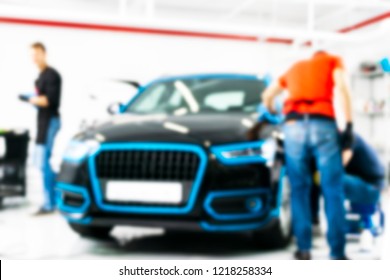 Blurred Abstract Image Of Man Worker With Car In Body Shop. Blur Car Auto Service. Car Bokeh. Blurred Background With Car In Garage. Vehicle Maintenance In Auto Repair Service. Blurry Service Station