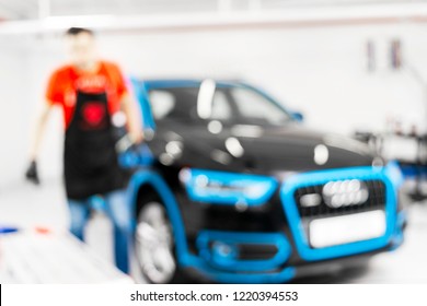 Blurred Abstract Image Of Man Worker With Car In Body Shop. Blur Car Auto Service. Car Bokeh. Blurred Background With Car In Garage. Vehicle Maintenance In Auto Repair Service. Blurry Service Station