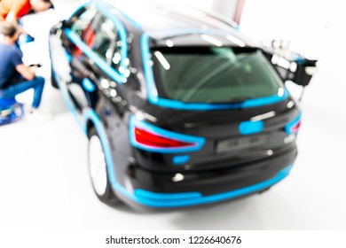 Blurred Abstract Image Of Man Worker With Car In Body Shop. Blur Car Auto Service. Car Bokeh. Blurred Background With Car In Garage. Vehicle Maintenance In Auto Repair Service. Blurry Service Station