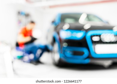 Blurred Abstract Image Of Man Worker With Car In Body Shop. Blur Car Auto Service. Car Bokeh. Blurred Background With Car In Garage. Vehicle Maintenance In Auto Repair Service. Blurry Service Station