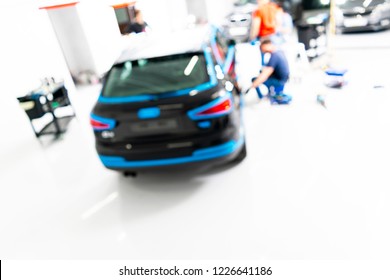 Blurred Abstract Image Of Man Worker With Car In Body Shop. Blur Car Auto Service. Car Bokeh. Blurred Background With Car In Garage. Vehicle Maintenance In Auto Repair Service. Blurry Service Station