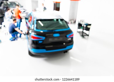 Blurred Abstract Image Of Man Worker With Car In Body Shop. Blur Car Auto Service. Car Bokeh. Blurred Background With Car In Garage. Vehicle Maintenance In Auto Repair Service. Blurry Service Station