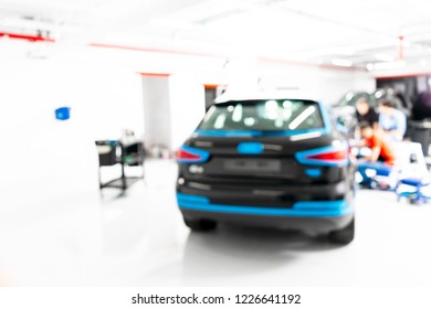 Blurred Abstract Image Of Man Worker With Car In Body Shop. Blur Car Auto Service. Car Bokeh. Blurred Background With Car In Garage. Vehicle Maintenance In Auto Repair Service. Blurry Service Station