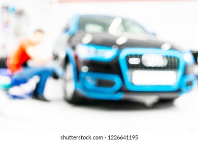 Blurred Abstract Image Of Man Worker With Car In Body Shop. Blur Car Auto Service. Car Bokeh. Blurred Background With Car In Garage. Vehicle Maintenance In Auto Repair Service. Blurry Service Station