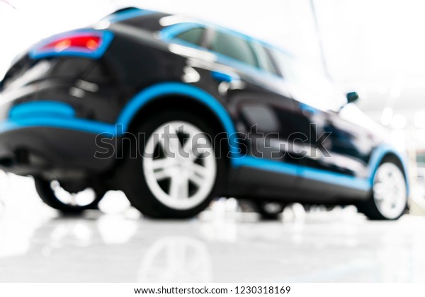 Blurred abstract image of man worker with car in\
body shop. Blur car auto service. Car bokeh. Blurred background\
with car in garage. Vehicle maintenance in auto repair service.\
Blurry service station