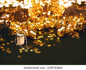 Blurred abstract shiny black background with champagne cork, golden tinsel and stars confetti close up. 
artistic grunge noise filter. selective focus - Powered by Shutterstock