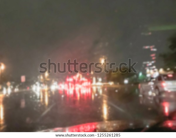 Blurred abstract\
stopped car at traffic light intersection and rear lights\
reflection on the rainy asphalt road. Defocused cityscape and\
transportation background in\
America