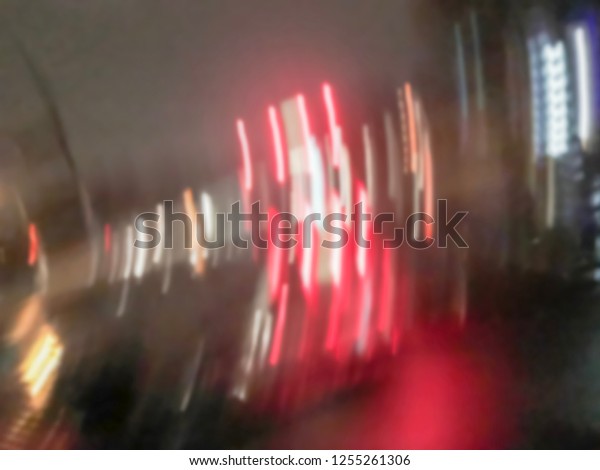 Blurred abstract\
stopped car at traffic light intersection and rear lights\
reflection on the rainy asphalt road. Defocused cityscape and\
transportation background in\
America
