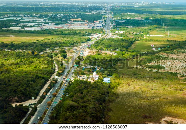 Blurred\
aerial view of the East coast of Yucatan Peninsula, Mexico. Green\
forest and traffic on a highway towards\
Cancun.