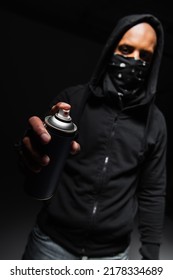 Blurred african american hooligan with mask on face holding spray paint on black background - Shutterstock ID 2178334689