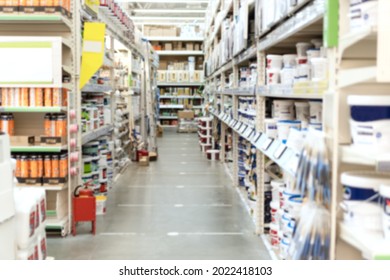 Blurred aisle and shelves with building and finishing materials in hardware store. View of hypermarket rows with paints. Shopping and trading background.