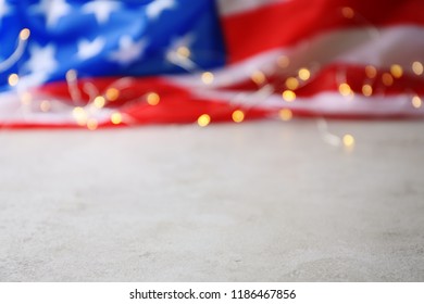 Blurred American Flag And Garland On Grey Table. Space For Text