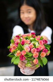 Blurred Of Asian Pre Teen Girl Giving A Beautiful Bouquet Of Pink And Red Roses To Camera. Smiling Young Pretty Girl Holding Big Bunch Of Colorful Flowers With Soft Focus. Kid Give Flowers To Someone.