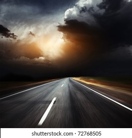 Blurred asphalt road and dark thunder clouds over it