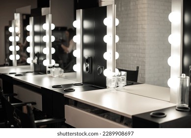 Blurred background of a beauty salon, a make-up table with lighting, cinema lights, interior of a hairdressing salon