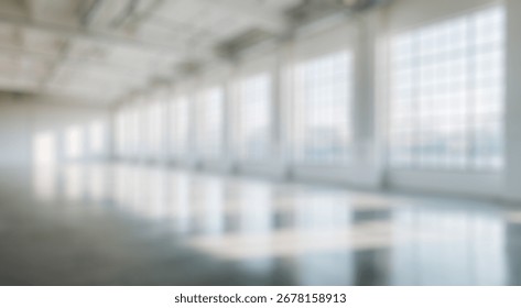 Blurred background of bright and spacious empty industrial warehouse interior with large windows and natural light streaming across polished concrete floor