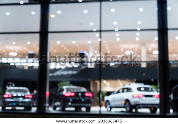 Blurred background with\
car dealership exterior. Abstract blurred photo of modern building\
motor showroom. Blur car show room office bokeh lights. Automobile\
retail shop