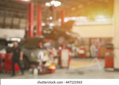 Blurred Background Of Car Technician Repairing The Car In Garage,mechanics Fixing Machine In A Workshop,auto-car Suspension Detail Of Lifted Automobile At Repair Service Station,vintage Color.