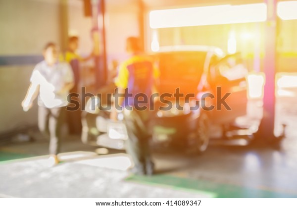 Blurred background of car technician repairing the\
car in garage,mechanics fixing car in a workshop background,car\
suspension detail of lifted automobile at repair service\
station,vintage color.