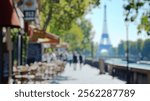 Blurred background of a charming scene of a parisian sidewalk by the seine river, featuring vibrant greenery and blurred figures enjoying the lively atmosphere of the city.