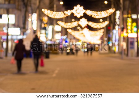 Blurred background of christmas street lights with two people strolling with shopping bags in Vienna, Austria