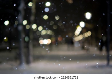 Blurred background. City view, lights, falling snow, night, street, bokeh spots of headlights of moving cars. Diffuse Urban backdrop winter scenery of street in city at night. Lantern light, snowfall - Shutterstock ID 2224851721