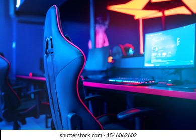 Blurred background computer pc, keyboard armchair, blue and red lights. Concept online eSports arena for gamer playing tournaments. - Shutterstock ID 1546062602