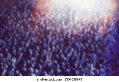 Blurred Background With Concert Audience Partying In Bright Blue Stage Lights.Huge Concert Crowd Shot From Above.Many Young People Waving With Hands To Favorite Dj Set In The Club