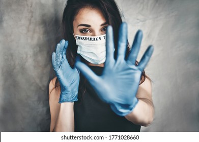 Blurred background. Conspiracy. Beautiful young woman in a white medical mask and blue protective gloves. Woman showing hand stop gesture. Oil paints illustration painting background.