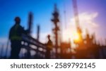 Blurred Background of Construction Workers Silhouetted Against Sunset in Urban Development Site with Crane and Scaffolding. Blurry Background For Design Projects.