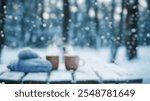 Blurred background of a cozy winter scene featuring warm mittens and cups of beverage on a snowy table, inviting a sense of tranquility and comfort in the cold outdoors.