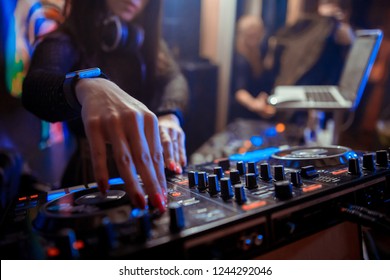 Blurred background with dj girl playing music and scratching tracks on professional dj midi controller.Modern disc jockey digital audio equipment for concerts or house party event.Stage lighting