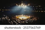 Blurred background of a dramatic view of an iconic boxing arena with a spotlight illuminating the ring, surrounded by an excited crowd, capturing the essence of the sport.