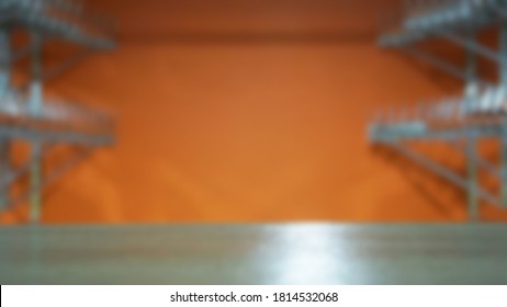 blurred background empty public wardrobe, no one, orange wall, table surface and empty dressing room hangers                             