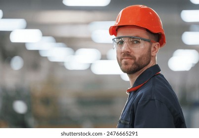 Blurred background. Factory worker is indoors with hard hat. - Powered by Shutterstock