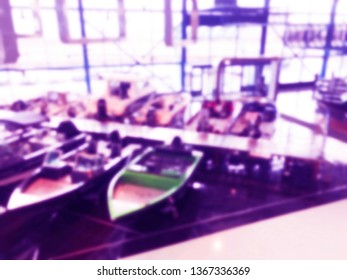 Blurred Background With Fishing Motor Boat In The Dealership Store. Blur Motorboat Showroom Background. Bokeh Light