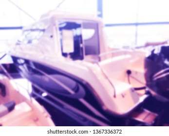 Blurred Background With Fishing Motor Boat In The Dealership Store. Blur Motorboat Showroom Background. Bokeh Light