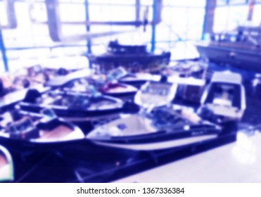 Blurred Background With Fishing Motor Boat In The Dealership Store. Blur Motorboat Showroom Background. Bokeh Light